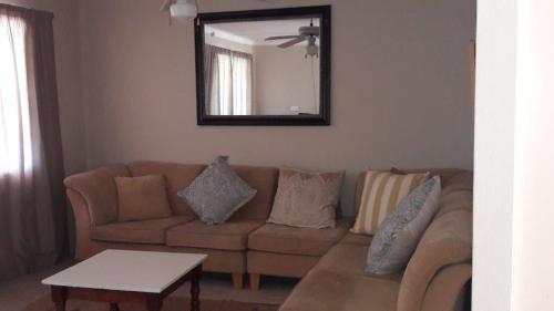 a living room with a brown couch and a mirror at Under The Oak in Underberg