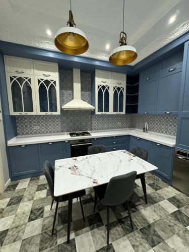 a kitchen with blue cabinets and a white table and chairs at Bilgeh Old House Villa in Baku