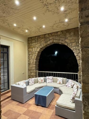 a living room with a couch and a stone wall at Bilgeh Old House Villa in Baku
