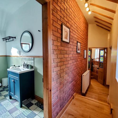 a bathroom with a sink and a brick wall at Hebron Rural converted chapel in Nantglyn