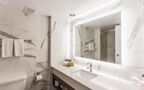 a white bathroom with a sink and a mirror at Chateau Cartier Hotel & Resort, an Ascend Collection Resort in Gatineau