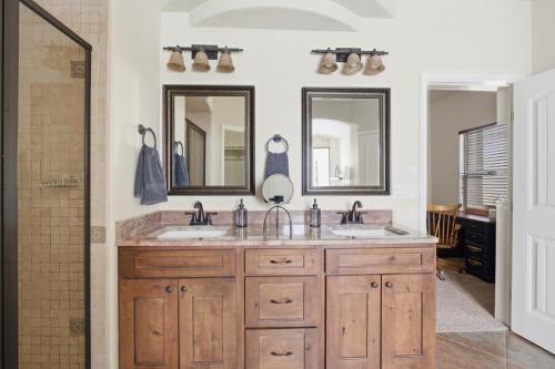 a bathroom with two sinks and two mirrors at The Palo in Alamogordo