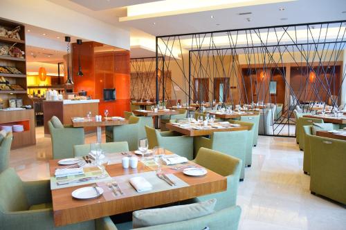 a restaurant with wooden tables and green chairs at Yas Plaza Marina by IHG in Abu Dhabi