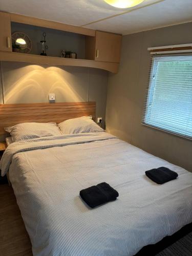 a bedroom with a large bed with two black towels on it at Prachtige stacaravan met heerlijke overkapping in Eext