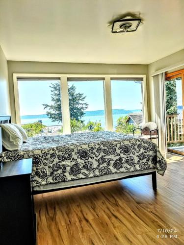 a bed in a room with large windows at Saltwater Beach Home with Ocean View in Des Moines