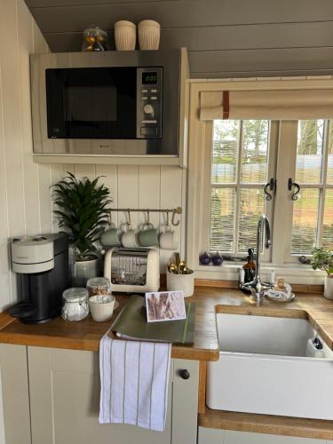 a kitchen counter with a sink and a microwave at The Hut at Claston in Stoke Edith