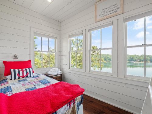 a bedroom with windows and a bed with a red blanket at Central Perk - Pet Friendly, Luxury Cabin Feel, Kayaksand Coffee! in Crane Hill