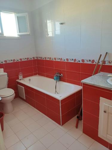 a red bathroom with a tub and a toilet at Maryline house in Bizerte
