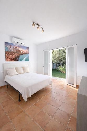 a white bedroom with a bed and a large window at Finca Feliciano in Novo Sancti Petri