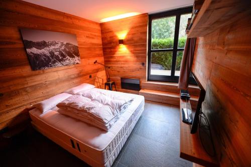 ein Schlafzimmer mit einem Bett in einem Holzzimmer in der Unterkunft Chamonix Balcons du Mont Blanc in Chamonix-Mont-Blanc