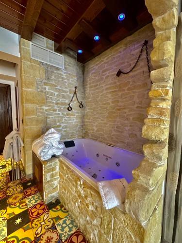 a bath tub in a room with a stone wall at Hotel SPA El Lagar de Isilla in La Vid y Barrios