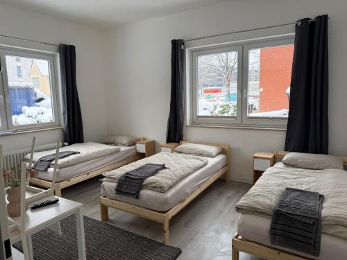 a room with three beds and two windows at Hostel & Monteurzimmer bei KuK in Hamburg