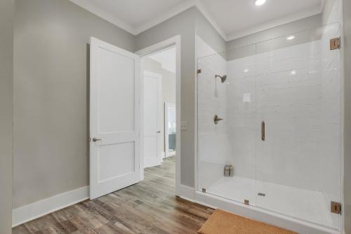 a white bathroom with a shower and a door at Mallard Pointe Unit 200- Luxury Condo- Conveniently Located! in Cullman