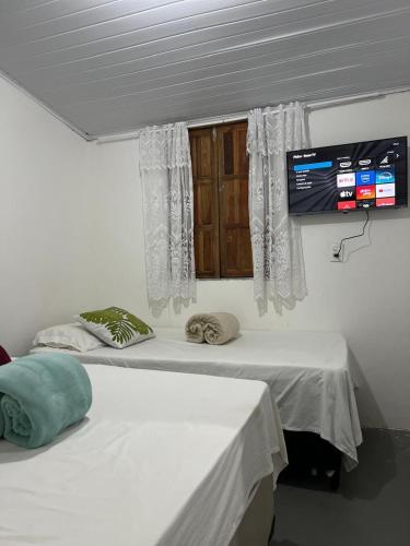 a room with two beds and a tv on the wall at Casa Recanto- Vila Uryah in Caraíva