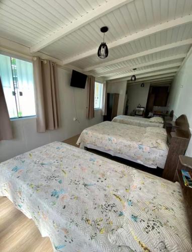 a bedroom with two beds and a television in it at Casa do Aconchego - Quitinete I in Governador Celso Ramos