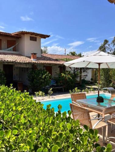 a patio with a table and umbrella next to a pool at Casa Recanto- Vila Uryah in Caraíva