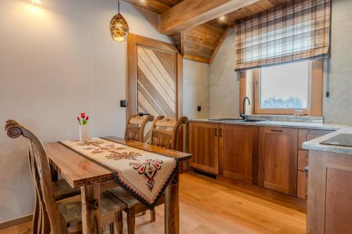a kitchen with a wooden table and chairs and a window at Domki Góralska Przystań in Białka Tatrzańska