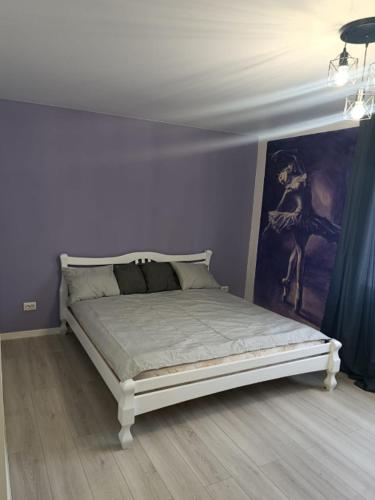 a bed in a room with a purple wall at Loft Like View in Izmail