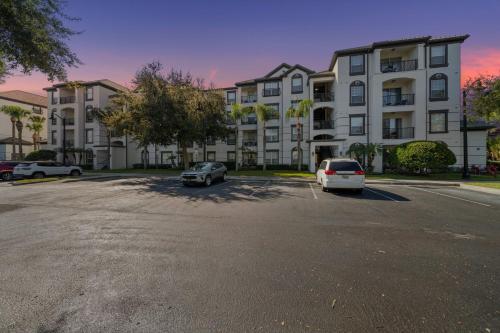 two cars parked in a parking lot in front of a building at Deluxe 3 Bedroom Apartment 404 in Orlando