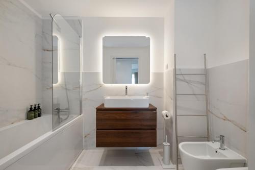 a white bathroom with a sink and a mirror at Oceanfront Bliss - Atlantico residences in Câmara de Lobos