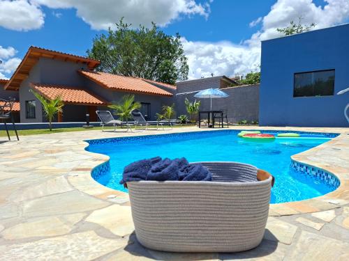 a swimming pool with a wicker basket in front of a house at Pousada Aroma de Café em Socorro-SP in Socorro