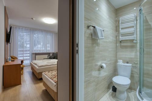 a bathroom with a toilet and a shower and a bedroom at Willa Świerkowa in Karpacz