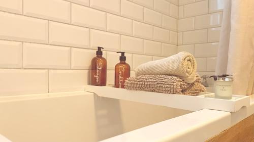 a bathroom shelf with two bottles and a towel at Beehive Cottage in Beccles