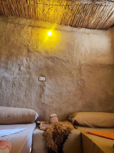 a room with two beds and a light on the wall at Historical Mayor's House in Qasr Al Farafirah