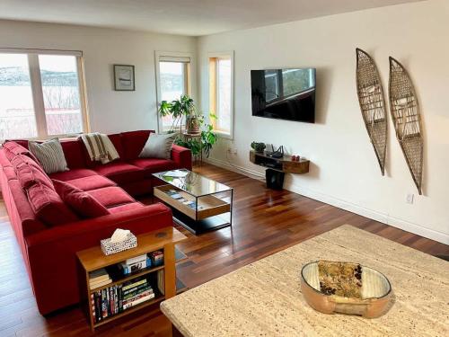 a living room with a red couch and a tv at Aurora views from 2 br apartment by lake in Yellowknife
