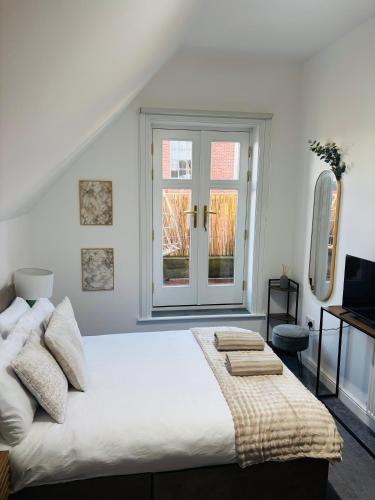 a white bedroom with a large bed and a window at The Luxe Haven Penthouse - Sleeps 4 Apartment Nottingham City Centre in Nottingham