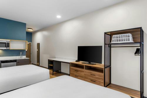 a bedroom with two beds and a desk with a tv at StudioRes by Marriott Jacksonville Orange Park in Orange Park