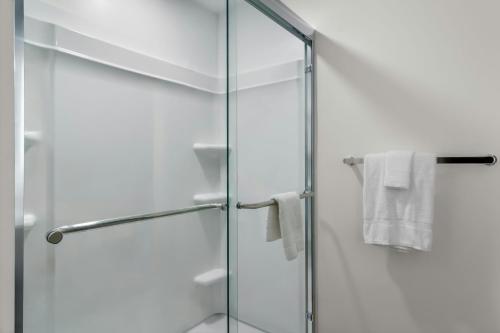 a glass shower with white towels in a bathroom at StudioRes by Marriott Jacksonville Orange Park in Orange Park