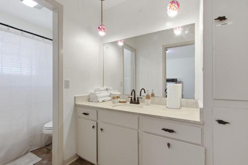 a white bathroom with a sink and a mirror at Rustic Retreat 5-BR Home with Backyard Oasis in Baton Rouge