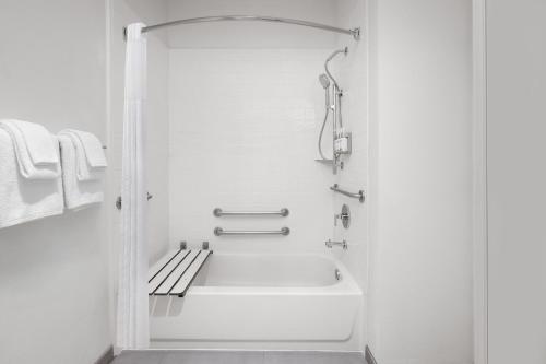 a white bathroom with a tub and a bench at Garner Hotel Liberty Lake by IHG in Liberty Lake
