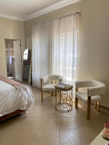 a bedroom with a bed and two chairs and a table at Andisa Airport Escape in Kempton Park