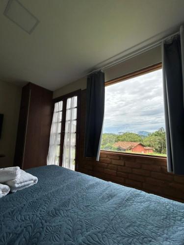 a bedroom with a bed and a large window at Chalé do Riacho in Nova Friburgo