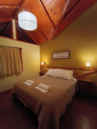 a bedroom with a large bed with two towels on it at Aldea Aliwen in Trevelín
