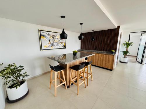 a kitchen with a counter and stools in a room at Depa Familiar con cochera 6 min Centro Médico y Catedral in Guadalajara