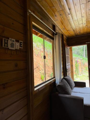 a bedroom with a couch and a window in a room at Cabana Pouso Sereno in Domingos Martins