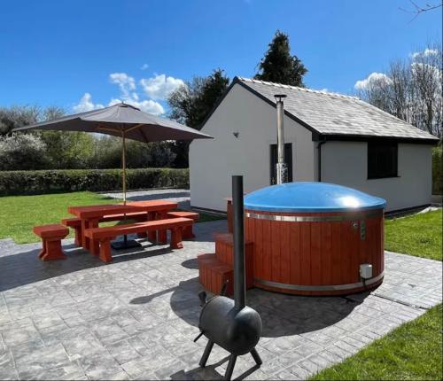 a hot tub and a picnic table and an umbrella at The Farmhouse at Moss Bank Farm in Wrexham