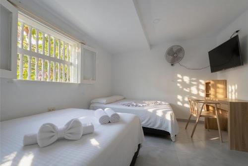 two beds in a white room with a window at Hotel Getsemaní Central in Cartagena de Indias