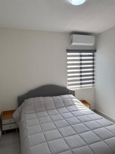 a bedroom with a bed with a white comforter and a window at Modern House with Mini-Splits in Chihuahua