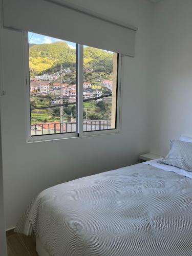 a bedroom with a white bed and a large window at Cozy Noia in Machico