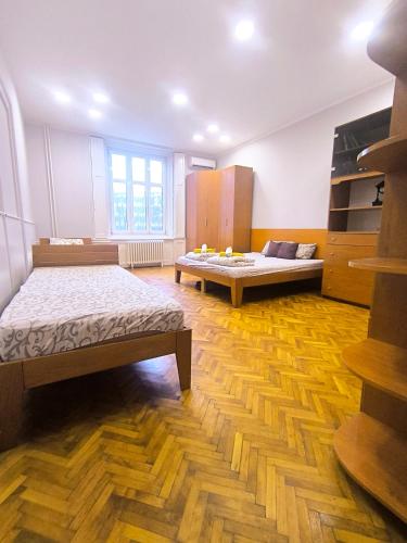 a large room with two beds and wooden floors at Downtown apartment in walk zone with 3 bedrooms and garage in Novi Sad