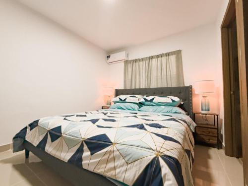 a bedroom with a bed with a blue and white comforter at Relaxing & New Retreat 3 bedroom riviera Verde in Santo Domingo
