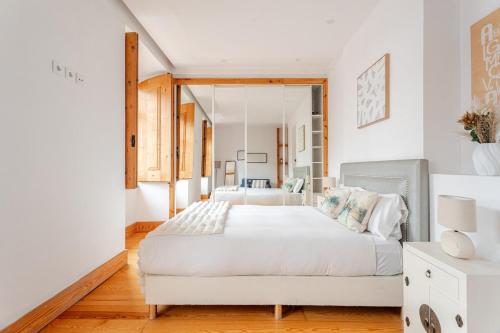 a bedroom with a white bed and a mirror at Cais Sodré Spacious Apartment in Lisbon
