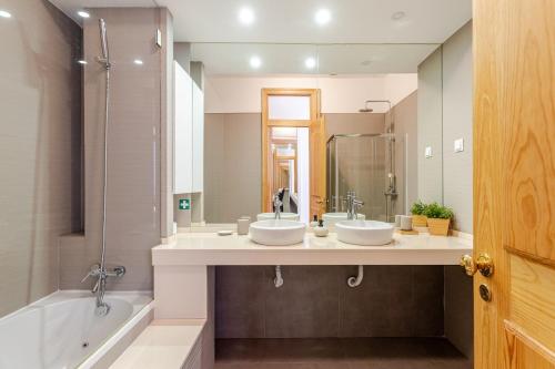 a bathroom with two sinks and a tub and a mirror at Cais Sodré Spacious Apartment in Lisbon