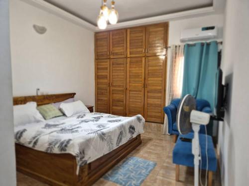 a bedroom with a bed and a blue chair at Appartement moderne 2 chambres Grand-Bassam, Pharmacie Yélé in Moosou