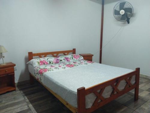 a bed in a bedroom with a fan on the wall at Cabaña Óga Pora' in Puerto Yeruá