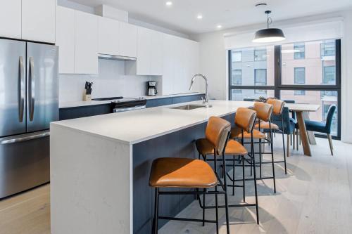 a kitchen with a bar with stools and a sink at Alpine Living - Modern 2 Bedroom Condo in Revelstoke